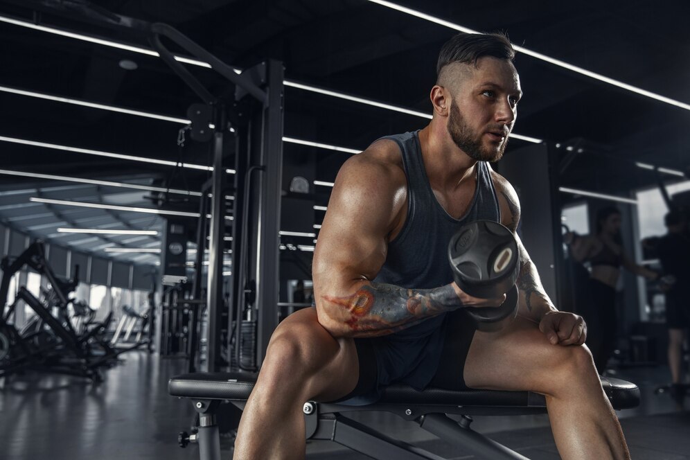 Muscular man lifting dumbbells in a modern gym.